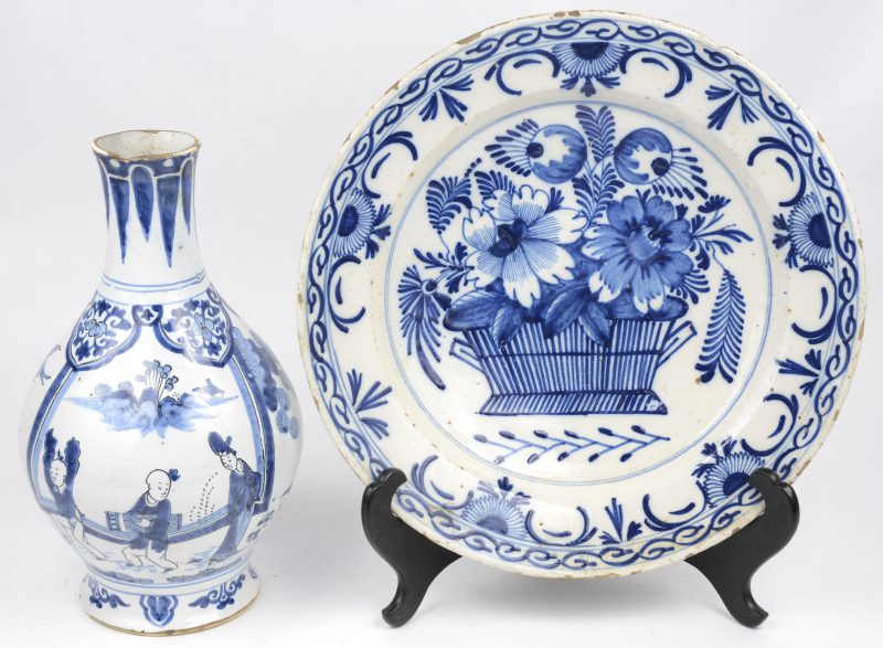 Een aardewerken schotel met blauw op wit decor van een bloemenmand in het plat. XVIIIe eeuw. Bijgevoegd een aardewerken vaas met blauw op wit Chinees decor. gat in de bodem en randschade.
