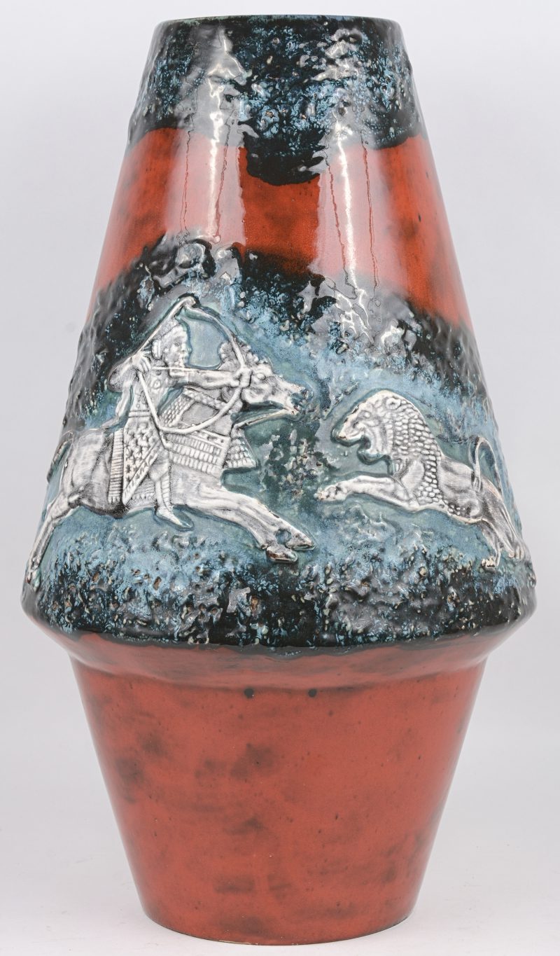 Een grote designvaas van meerkleurig geglazuurd aardewerk met een jachtscène in laagreliëf. Onderaan genummerd. Jaren ‘60.