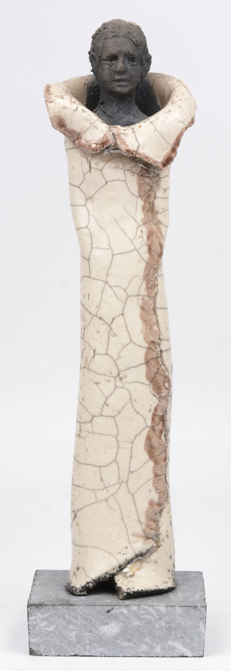 Een modern beeldje van geglazuurd aardewerk op een natuurstenen sokkel.