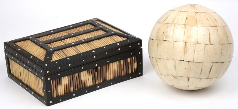 Een ebbenhouten kistje, versierd met ingelegde stipjes van ivoor en bekleed met stekels van een stekelvarken. Bijgevoegd een bal, bekleed met benen plaatjes.