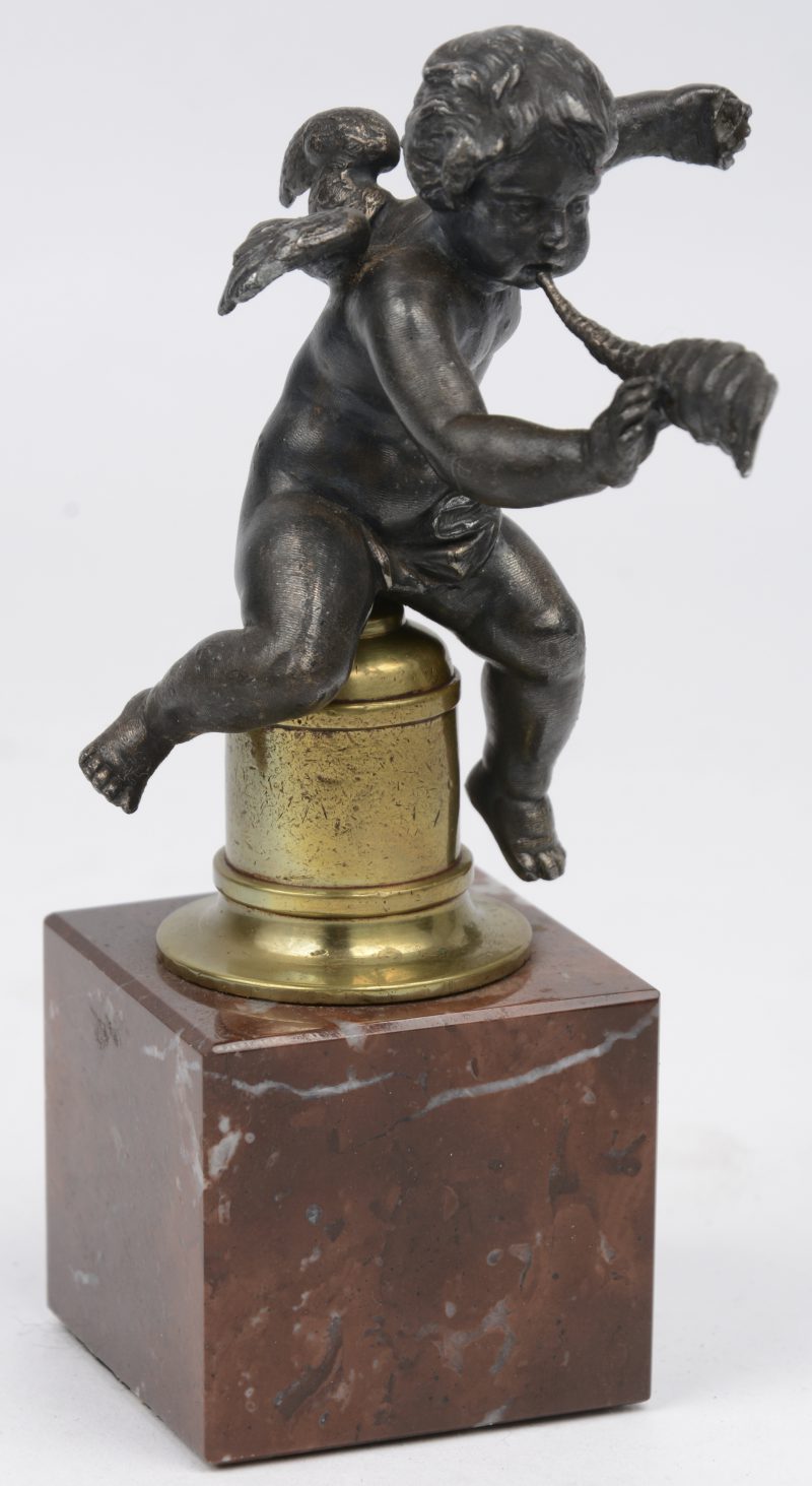 “Engeltje met hoorn”. Een klein bronzen beeldje op sokkel van rood marmer.