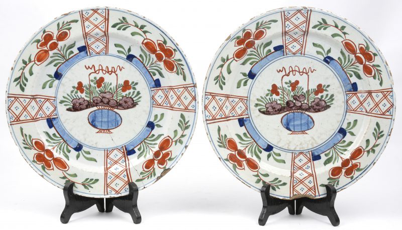 Een paar Delftse borden van polychroom aardewerk. Op het plat versierd met een bloemenmand en op de vleugel met bloempotten in cartouches. Eén met grote randschilfer, één met een haarscheur.