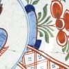 Een paar Delftse borden van polychroom aardewerk. Op het plat versierd met een bloemenmand en op de vleugel met bloempotten in cartouches. Eén met grote randschilfer, één met een haarscheur.