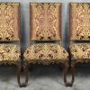 Een reeks van acht gesculpteerde stoelen en twee armstoelen in barokke stijl met gouden en bordeauxrode bekleding.