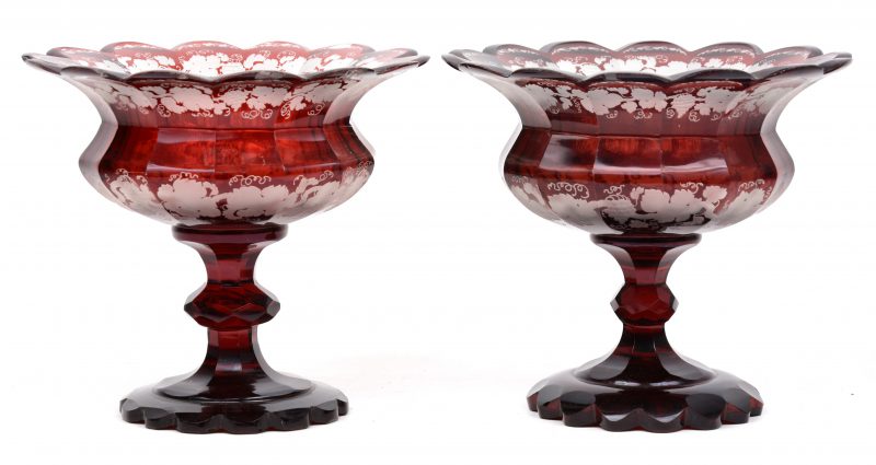 Een paar siercoupes van rood gedubbeld glas met geslepen kleurloos decor van wijnranken. Enige randschade.