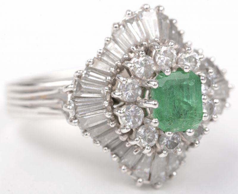 Een 18 K witgouden ring bezet met briljanten met een gezamenlijk gewicht van +- 2 ct. en een centrale smaragd van +- 1 ct.
