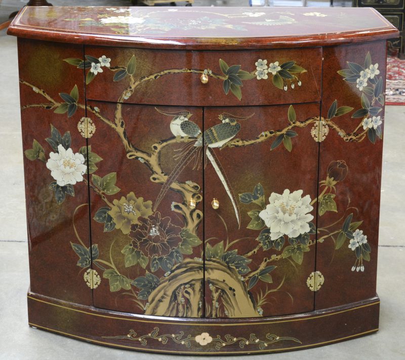 Een gelakt Chinees meubeltje met twee deurtjes en een lade en versierd met een decor van vogels en bloemen.