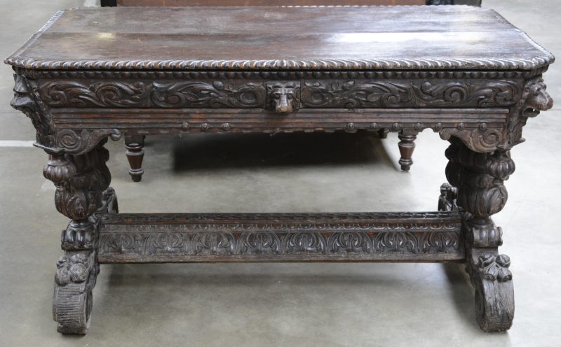 Een antieke tafel in renaissancestijl, rijkeleijk uitgewerkt met balusterpoten, vruchten en leeuwenkoppen. Ringen manco.