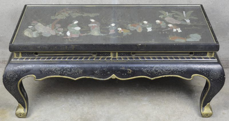 Een zwartgelakte Chinese salontafel met een pietra dura decor van diverse personages in het blad onder glas.