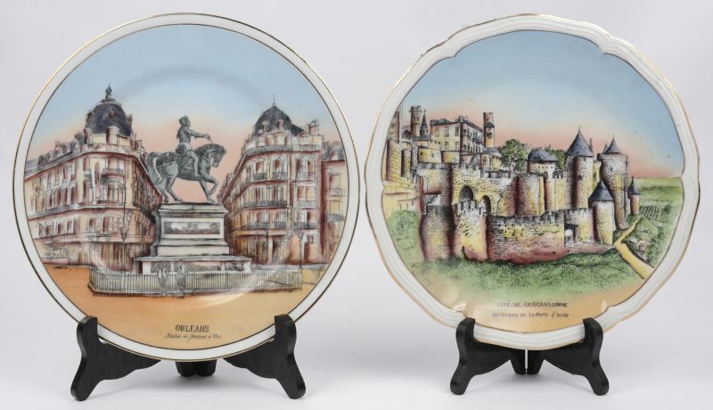 “Orleans” & “Cité de Carcassonne”. Twee porseleinen sierborden met een  handgeschilderd decor van het standbeeld van Jeanne d’Arc en het ander van Cité de Carcassonne.