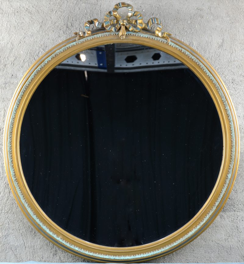 Een spiegel in verguld houten lijst in Lodewijk XVI-stijl met een strik  bovenaan.