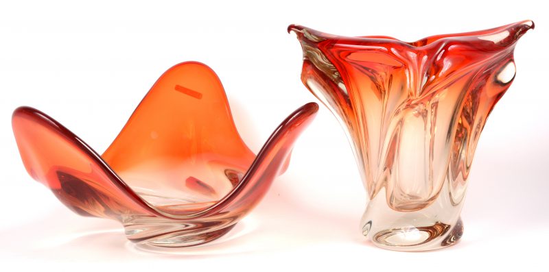 Een oranje kristallen designschaal en -vaas. De vaas met schilfer.