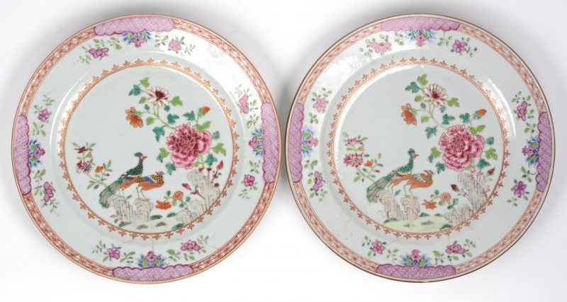 Een paar borden van Chinees porselein met een decor van pauwen en bloemen. XIXe eeuw. Beide gerestaureerd.