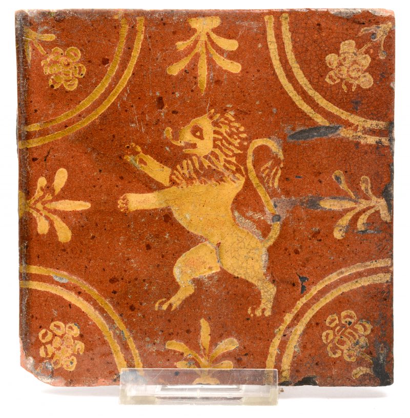 Een antieke geglazuurd aardewerken tegel met een leeuw in het decor.