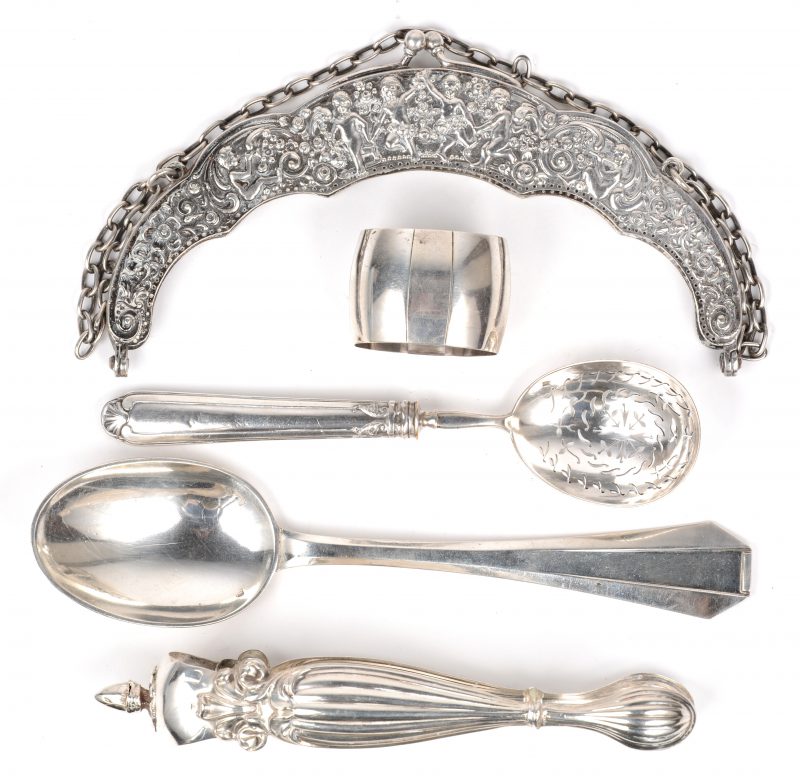 Een lot van vijf stuks zilver, bestaande uit de sluiting van een avondtasje, een strooilepel, een servetring, een suikertang en een lepel van Delheid.
