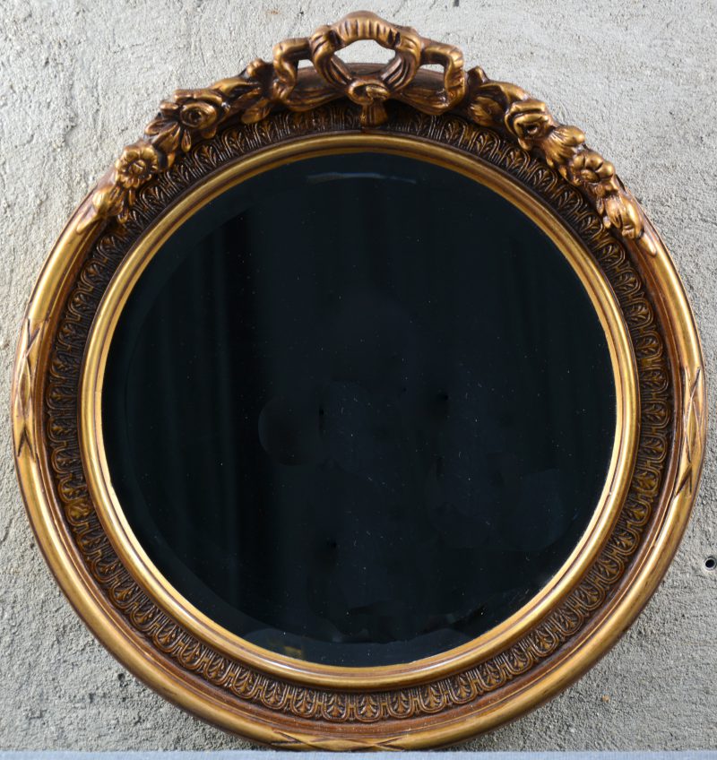 Een goudgepatineerde ronde spiegel in Lodewijk XVI-inspiratie.