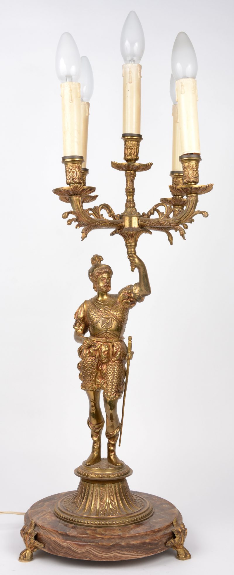 Een verguld bronzen kandelaar met vijf lichtpunten, gedragen door een ridder.