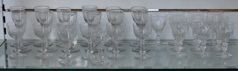 Een lot antiek glaswerk, bestaande uit acht glaasjes met gegraveerde decors, twaalf glaasjes met swirls in de voet en tien geslepen kleurloze glaasjes.