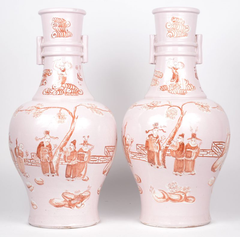 Een paar aardewerken Chinese lampenvoeten met personages in ijzerrood op roze achtergrond.