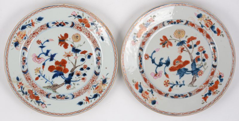 Een paar borden van Chinees porselein met decor van bloeiende planten en vogels. Tijdperk Qianlong. Eén beschadigd.