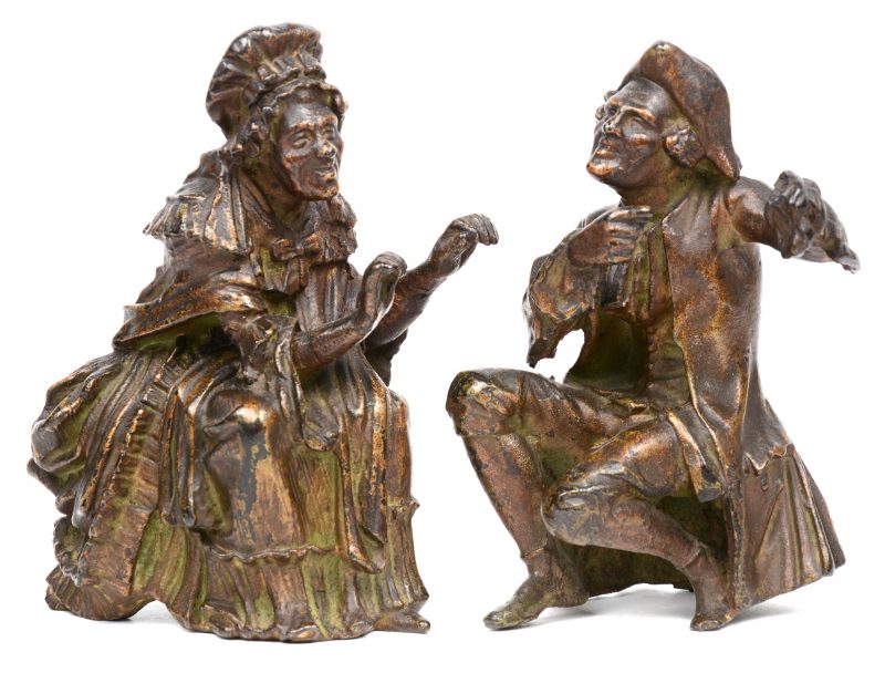 Twee kleine massieve bronzen beeldjes van een gehurkte oudere man en vrouw in XVIIIde eeuwse klederdracht. XIXde eeuw.