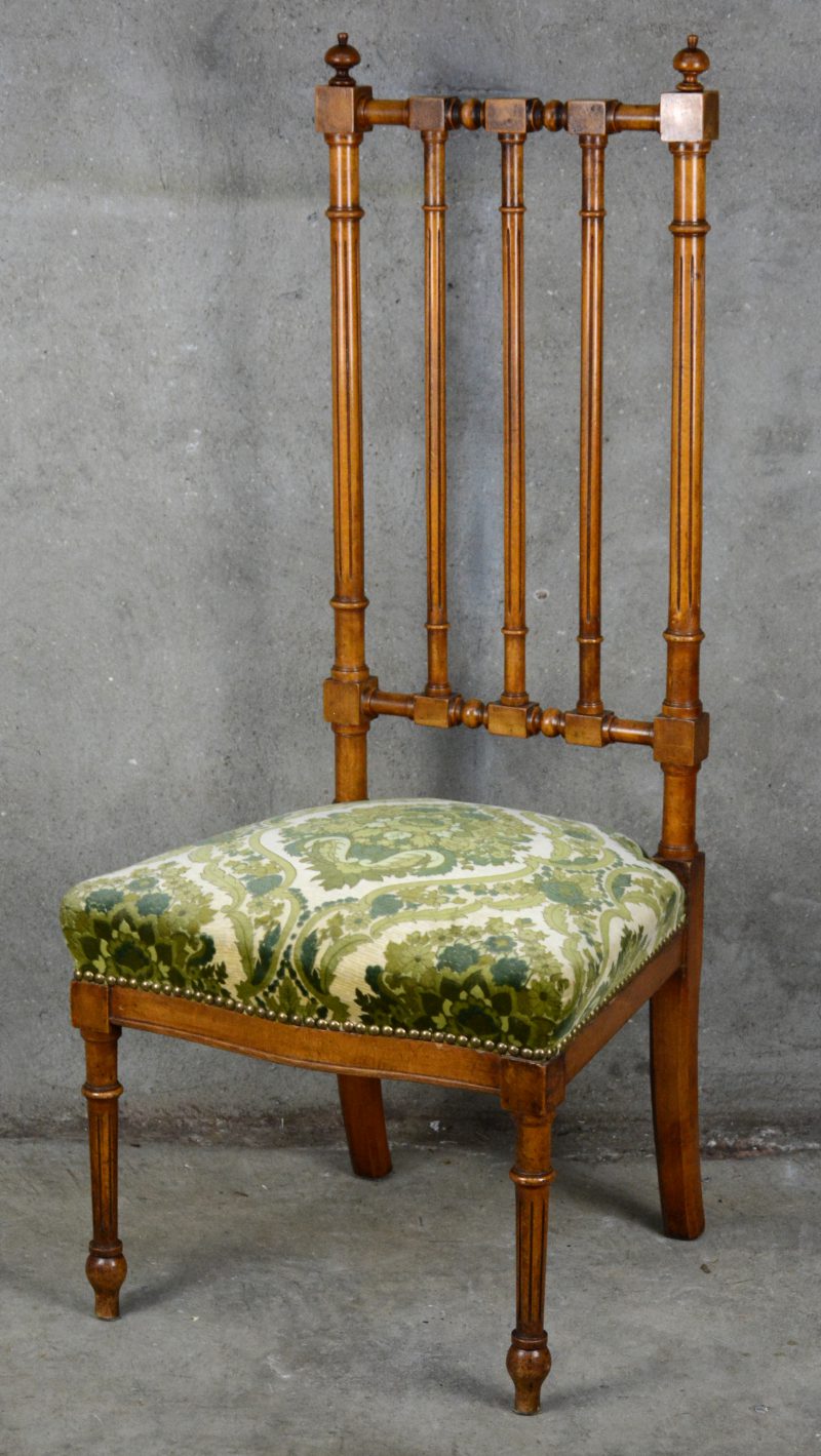 Een notenhouten lage stoel met fluwelen bekleding in Lodewijk XVI-inspiratie.