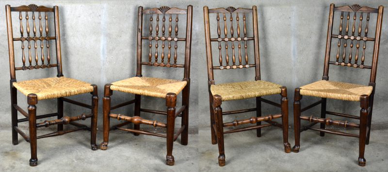 Een reeks van vier gedraaide houten stoelen met rieten zit.