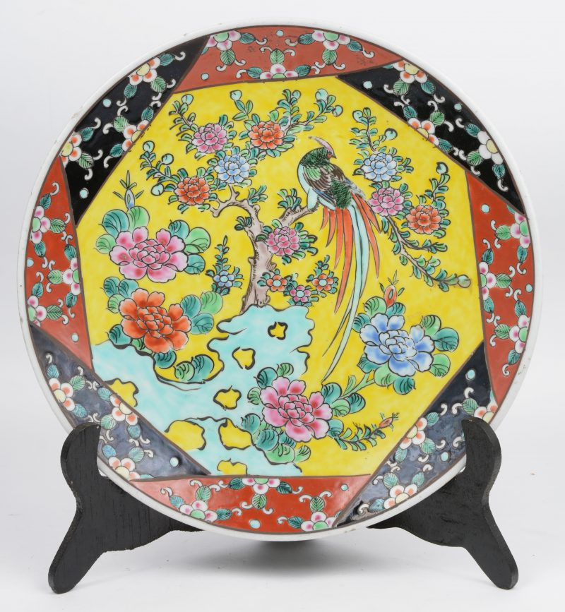 Een bord van Japans porselein met een decor van een goudfazant in een bloeiende pioenenstruik. Onderaan gemerkt.