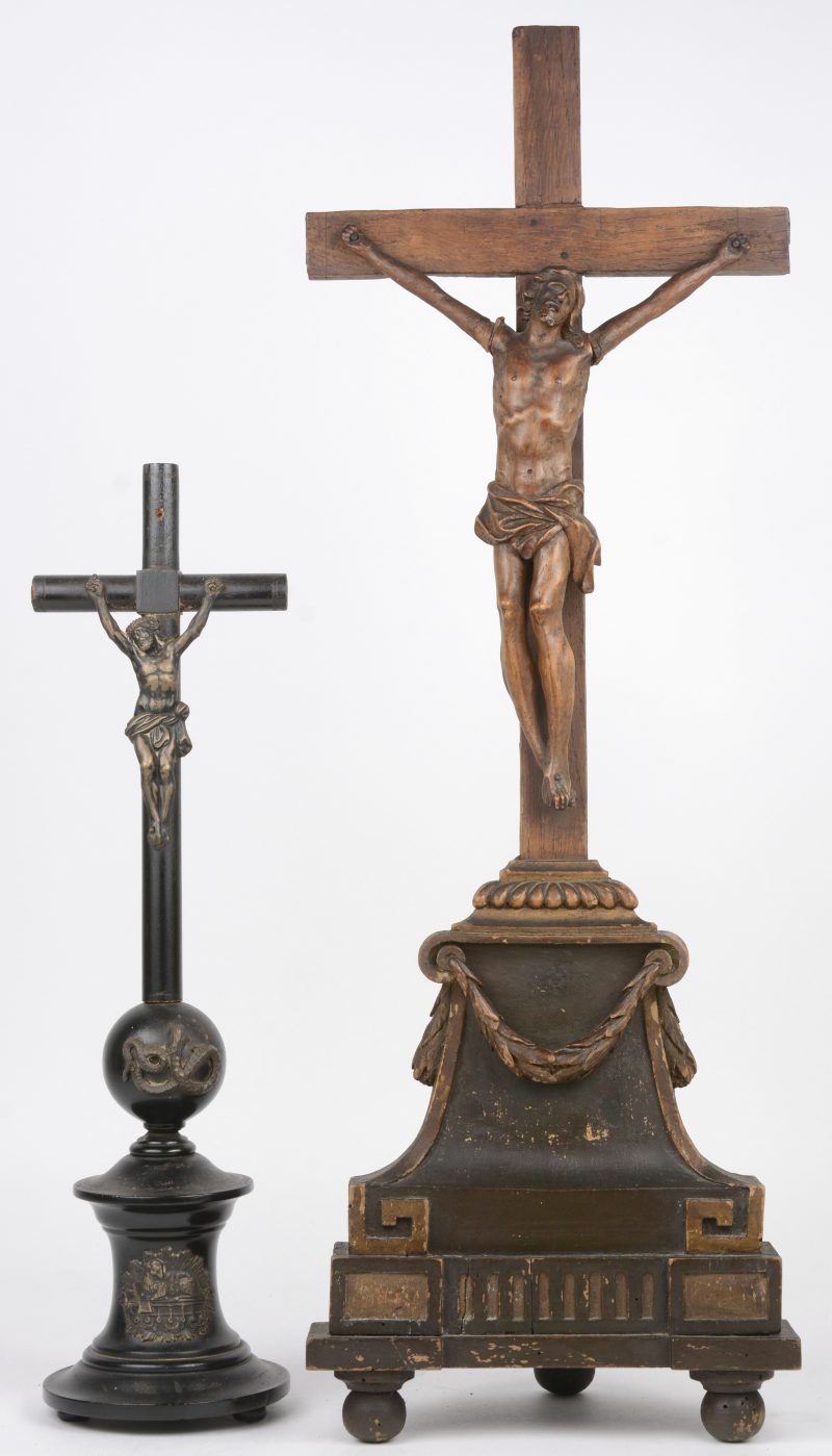 Een barok kruisbeeld van palmenhout (armen hersteld), op een gepolychromeerde Lodewijk XIV-voet. Het kruis vervangen door een rudimentair exemplaar. We voegen er een kruis van zwart perenhout met plaatzilveren Christus en Lam Gods aan toe.
