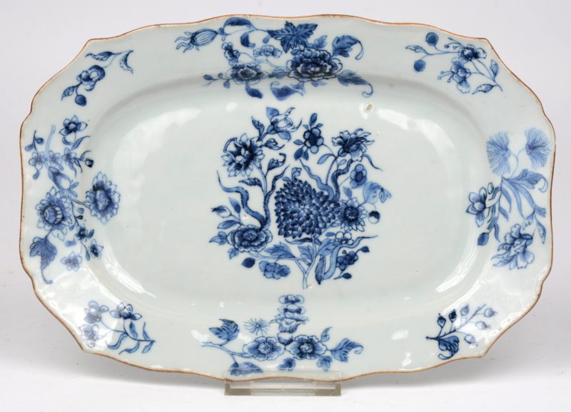 Een rechthoekig schoteltje van blauw en wit Chinees porselein. Decor van bloeiende takken, accoladerand. Tijdperk Qinglong.
