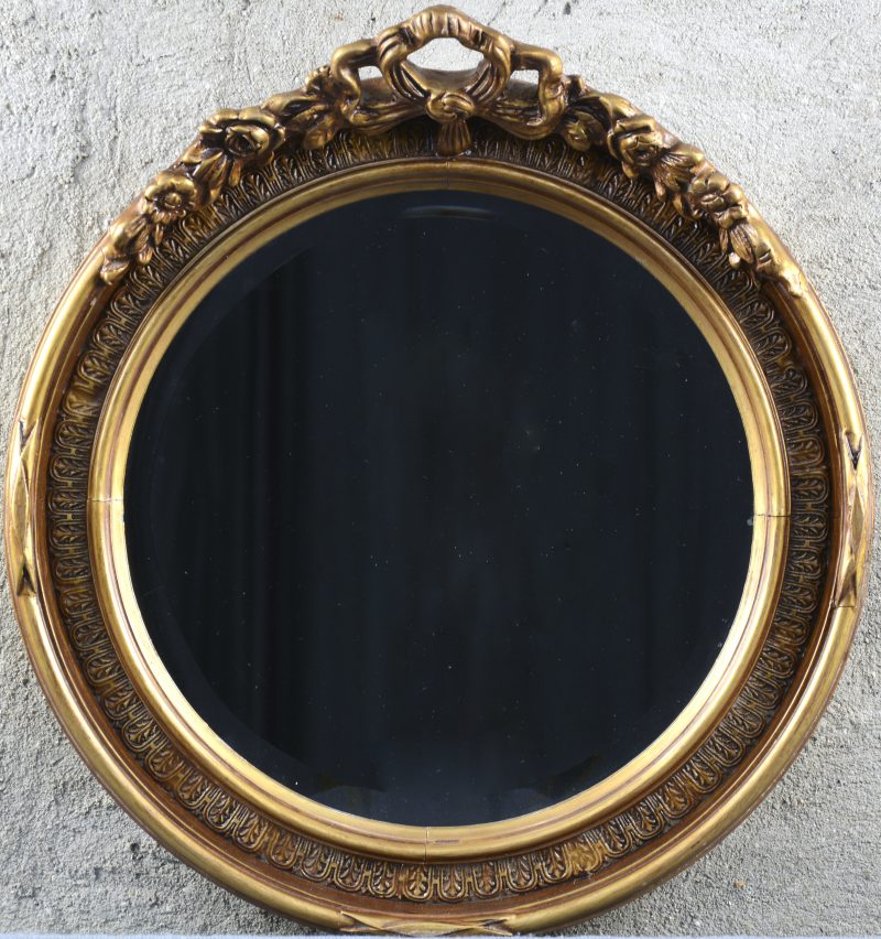Een ronde spiegel versierd met bloemen en een strik in de kuif.