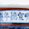 Een buikvaas van Chinees porselein met rood op blauw decor en met Ming-opschrift op de hals.