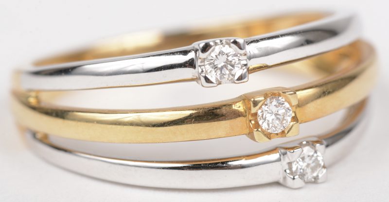 Een 18 K wit en geelgouden ring bezet met drie briljantjes met een gezamenlijk gewicht van +-0,10 ct.
