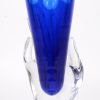 Een designvaas van blauw gedubbeld kristal, gedragen door een kleurloze hand. Model ‘Hera’, ontwerp van Alain Thiry. Beperkte serie van 100 exemplaren. gemerkt.