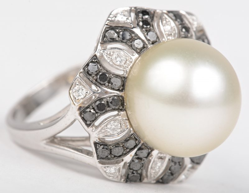Een 18 K witgouden ring bezet met witte en zwarte briljanten met een gezamenlijk gewicht van +- 0,61 ct. en een grote parel.