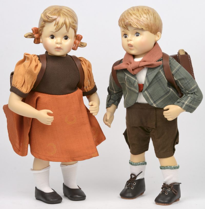 “Erster Schulgang (Mädchen) & (Junge)”. Een paar aangeklede porseleinen figuren gemerkt en uitgegeven door Goebel Porzellanfabrik. Genummerd Hum521 en Hum522.
