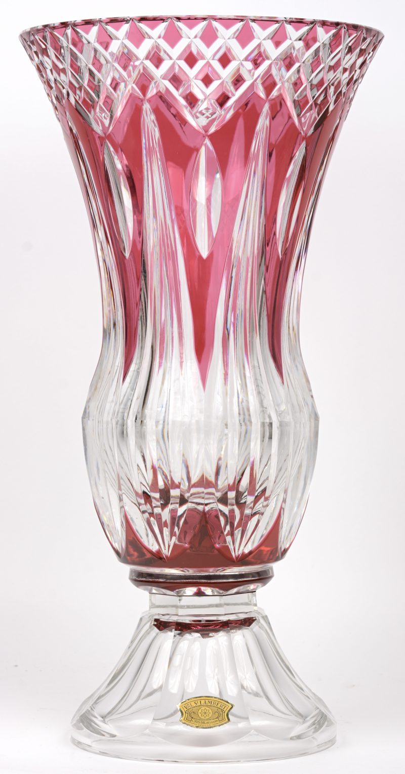 Een grote kelkvormige vaas met voetstuk van geslepen kristal, deels in de massa rood gekleurd. Onderaan gemerkt. En met label.