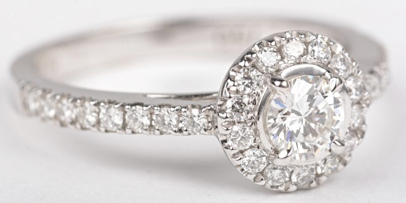 Een 18 K witgouden ring bezet met een centrale briljant van +- 0,20 ct. en briljanten met een gezamenlijk gewicht van +- 0,35 ct.