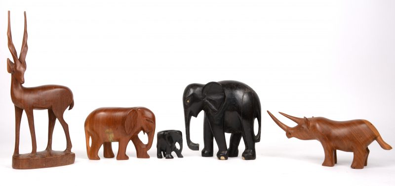 Vijf houten beeldjes in de vorm van diverse dieren. Drie olifanten, een neushoorn en een antilope.