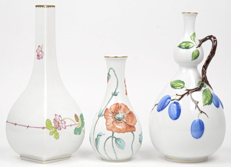 Drie diverse vaasjes van veelkleurig porselein met bloemen en pruimen versierd. Onderaan gemerkt.