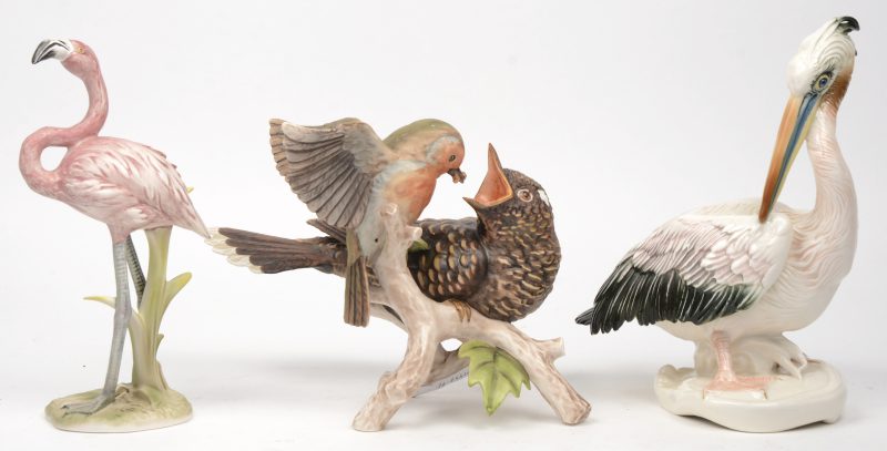 “Een vogel met een koekoeksjong, een flamingo en een pelikaan”. Drie beeldjes van porselein en biscuit. De eerste twee gemerkt van Goebel, de derde met een blauw merk.