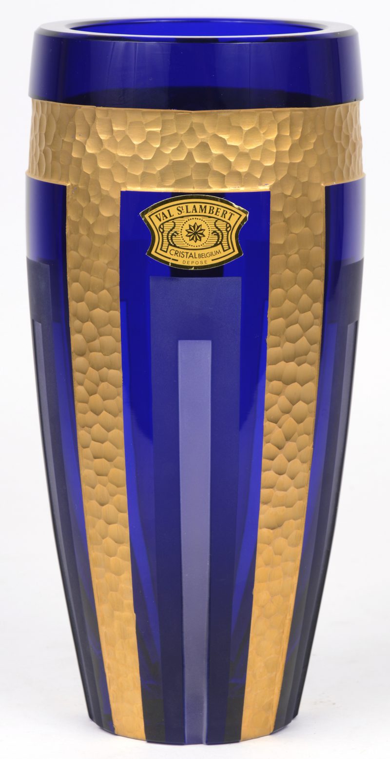 Een vaas van geslepen en deels gesatineerd blauw kristal met verguld motief. Gemerkt met label en gegraveerd onderaan met opschrift ‘design P. Dirs’.