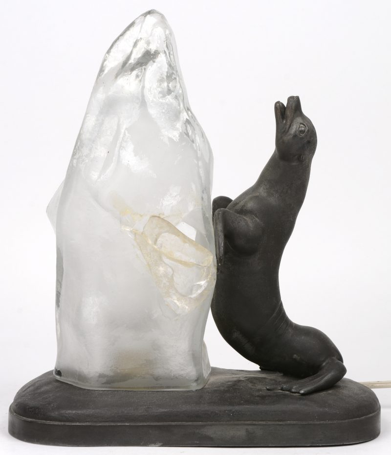 Een zamakken zeeleeuw tegen glazen ijsschots als schemerlampje. Glas beschadigd.