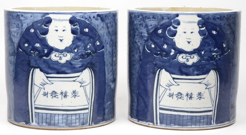 Een paar cilindervormige potten van Chinees porselein met een blauw-wit decor van figuren.