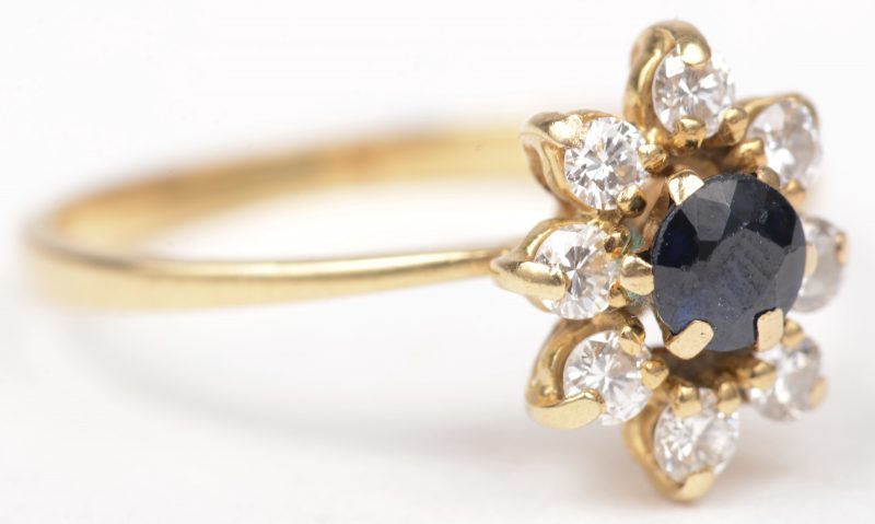 Een 18 K geelgouden ring bezet met briljanten met een gezamenlijk gewicht van +- 0,30 ct. en een centrale saffier van +- 0,20 ct.