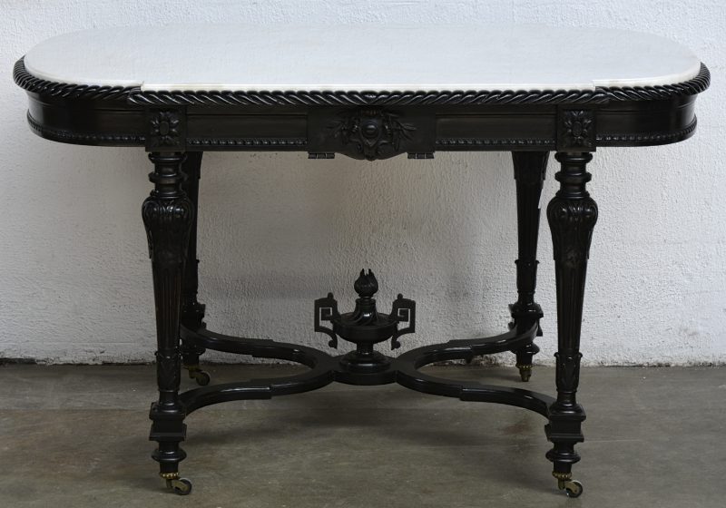 Een salontafel van zwart gelakt perenhout met een kruisverbinding in X, versierd met een gebeeldhouwde vaas. Gesculpteerde fluitpoten op wieltjes. Wit marmeren blad. Tijdperk Napoléon III.