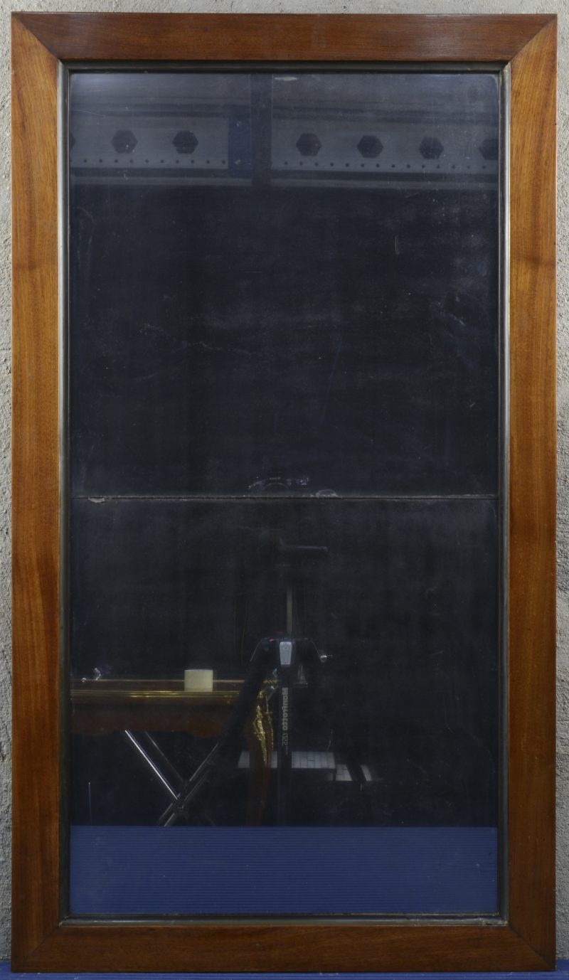 Een sobere rechthoekige spiegel van mahoniehout. Tweedelig spiegelglas. XIXde eeuw.