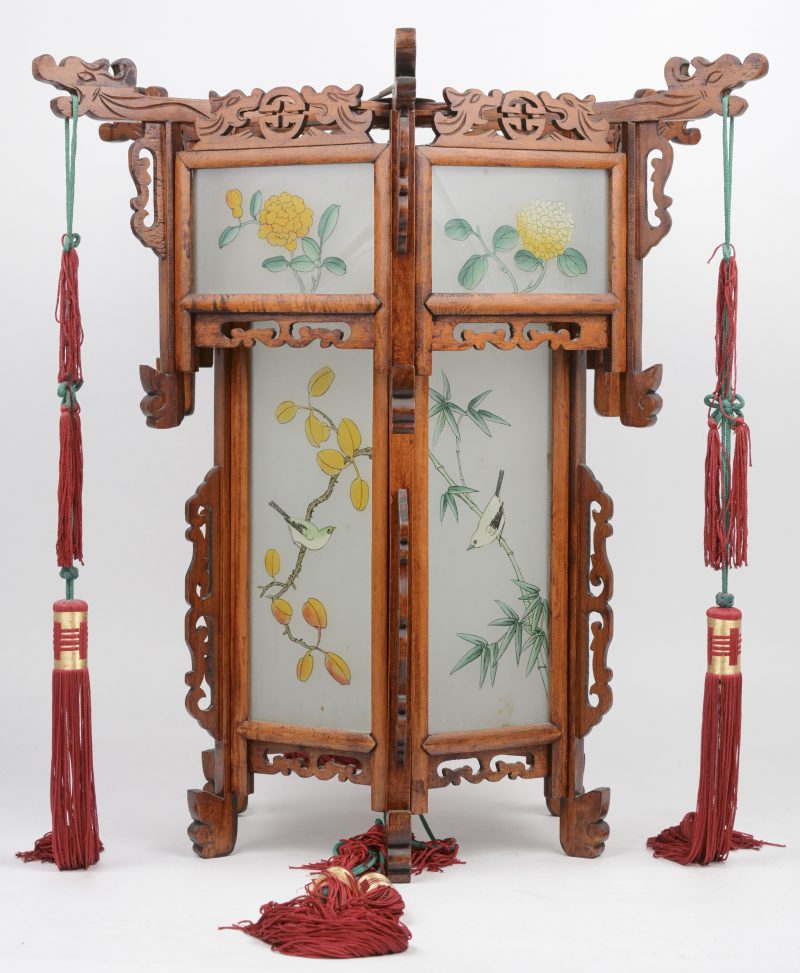 Een zeshoekige Chinese lantaarn van hout en glas met vogels op bloeiende takken in het decor en versierd met kwispels.