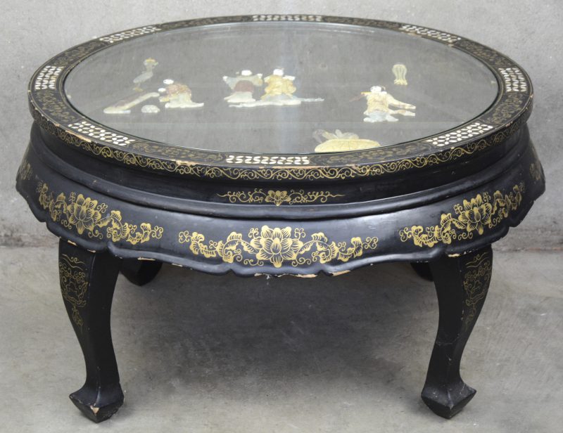 Een lage Chinese tafel van zwartgelakt hout met pietra dura decor van geisha’s onder glas.