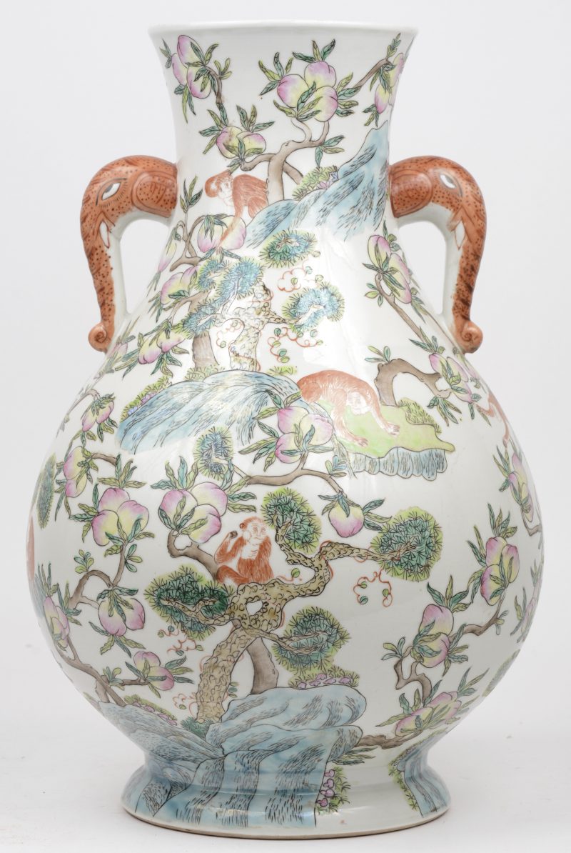 Een vaas van Chinees porselein met meerkleurif decor van perziken en aapjes in een landschap en met oren in de vorm van olifantenkoppen.